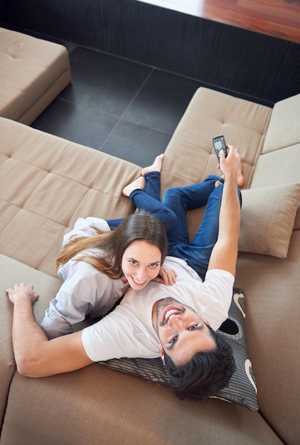 Giovane coppia rilassata che guarda la tv a casa nel luminoso soggiorno