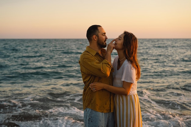Giovane coppia romantica che balla girando intorno al mare Vista sul mare al tramonto con un bel cielo Coppia romantica sulla spiaggia al tramonto dorato Coppia di innamorati che si divertono sulla spiaggia