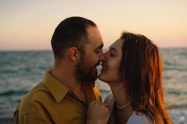 Giovane coppia romantica che balla girando intorno al mare Vista sul mare al tramonto con un bel cielo Coppia romantica sulla spiaggia al tramonto dorato Coppia di innamorati che si divertono sulla spiaggia