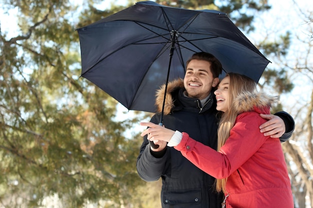 Giovane coppia romantica con ombrellone nel parco