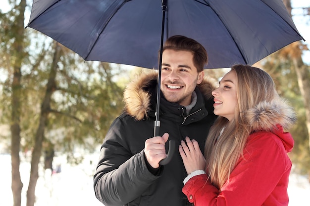 Giovane coppia romantica con ombrellone nel parco