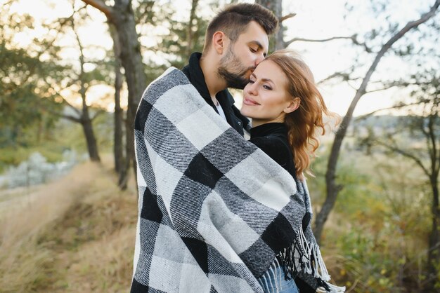 Giovane coppia romantica innamorata in un dolce abbraccio e si riscalda con un plaid