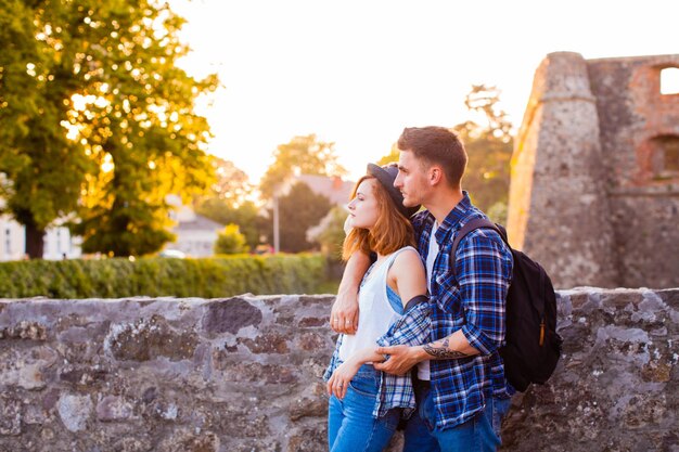 Giovane coppia sensuale in piedi che si abbraccia sullo sfondo del castello medievale. Il vecchio castello di Uzhhorod nei raggi del tramonto con la coppia amata in piedi di fronte