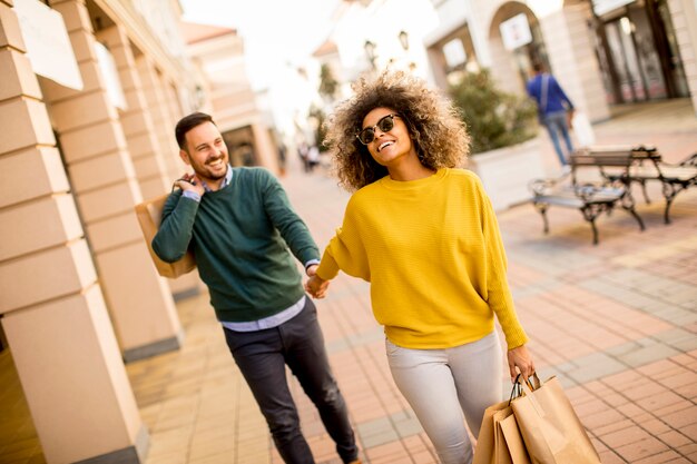 Giovane coppia sorridente shopping in una strada urbana