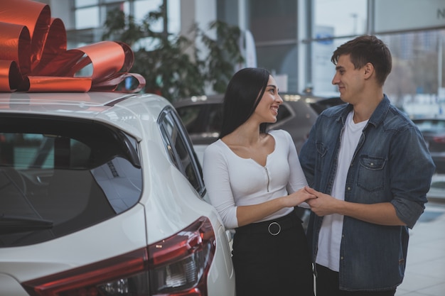 Giovane coppia sposata adorabile che compra insieme nuova automobile