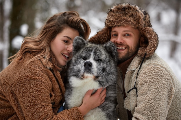 Giovane coppia sposata durante una passeggiata nella foresta invernale con un cane husky