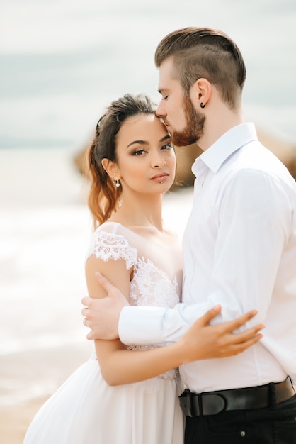 Giovane coppia sposo con la sposa su una spiaggia sabbiosa durante una passeggiata nuziale