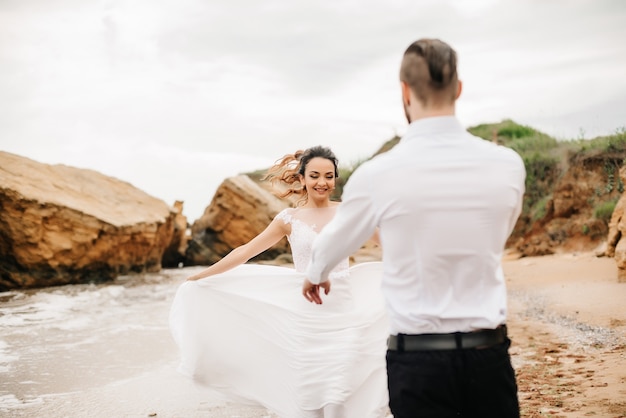 Giovane coppia sposo con la sposa su una spiaggia sabbiosa durante una passeggiata nuziale