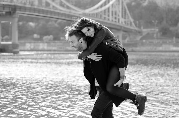 giovane coppia uomo e donna all'aperto in riva al fiume sullo sfondo del ponte