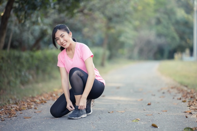 Giovane corridore asiatico della donna che lega i lacci delle scarpe, fitness Lifestyle e donne attive esercitano nel concetto di città urbana.