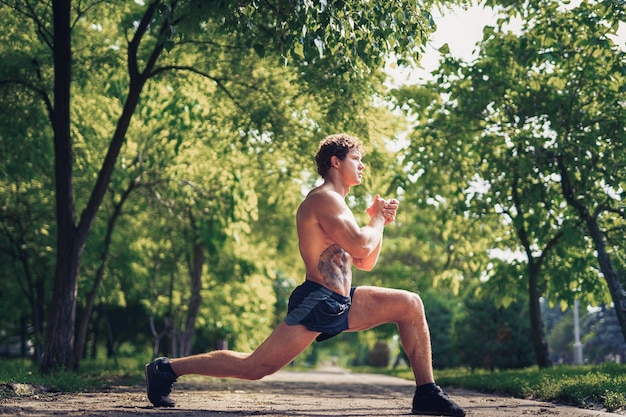 Giovane corridore dell'uomo di forma fisica che allunga le gambe prima della corsa