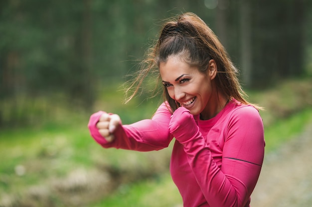 Giovane corridore femminile che si riscalda prima di correre e divertirsi al mattino nella foresta.