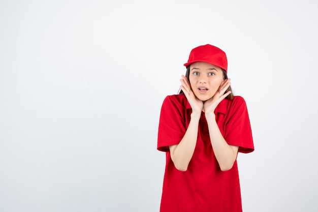 giovane corriere femminile in uniforme rossa che tiene il suo viso.