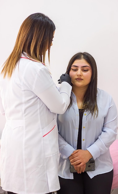 giovane cosmetologo con una maschera medica che lavora sul suo cliente