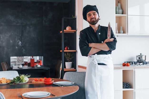 Giovane cuoco professionista in uniforme che fa insalata in cucina