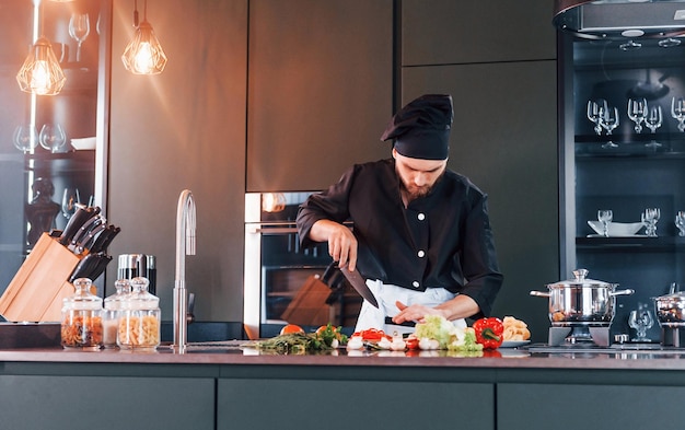 Giovane cuoco professionista in uniforme che lavora in cucina