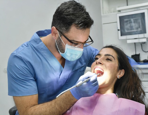 giovane dentista che esegue un trattamento orale su un giovane e bellissimo paziente