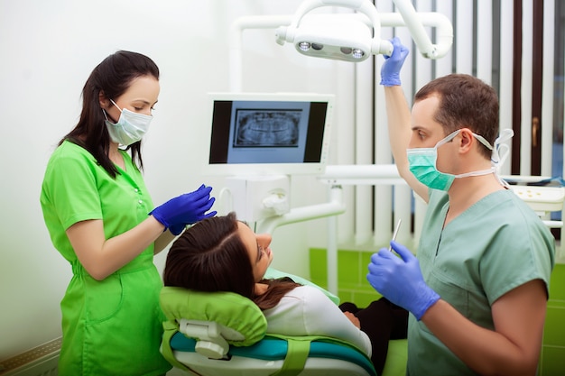 Giovane dentista che tratta un paziente femminile nello studio dentistico