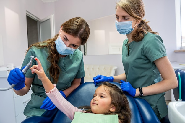 giovane dentista specializzata qualificata che lava i denti di un bambino piccolo che è stato portato alla reception. Il concetto di lavarsi i denti da latte