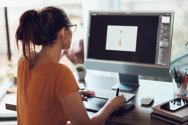 Giovane designer che lavora al computer nel suo studio di casa.