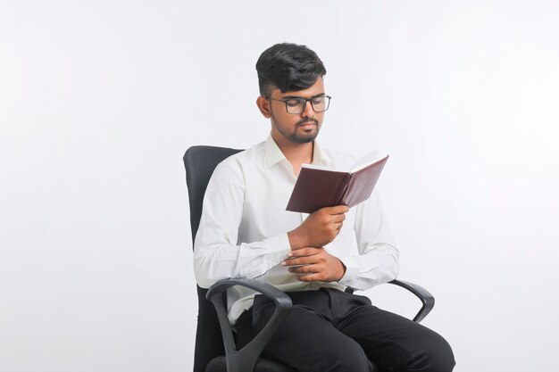 Giovane diario di lettura maschio indiano su sfondo bianco.