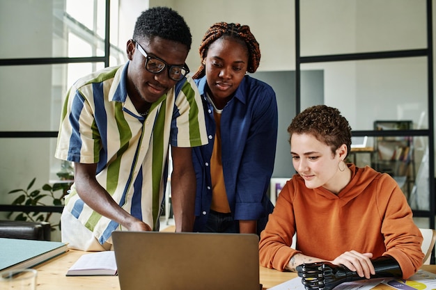 Giovane dipendente afroamericano che punta allo schermo del laptop