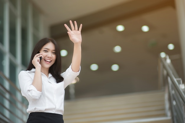 Giovane dirigente di donna asiatico che lavora con un telefono cellulare nell&#39;edificio per uffici