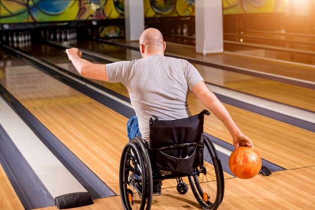 Giovane disabile in sedia a rotelle che gioca a bowling nel club