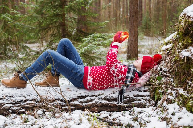 Giovane divertente in cappello rosso nella foresta di inverno