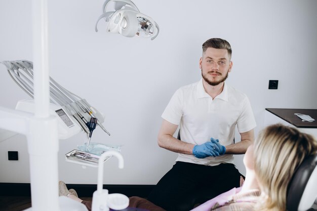 Giovane divertente ortodontista dentista uomo caucasico indossare abito che mostra la mascella morso denti xray per paziente donna seduta al dentista sedia da ufficio armadio interno vicino stomatologo Healthcare trattamento smalto