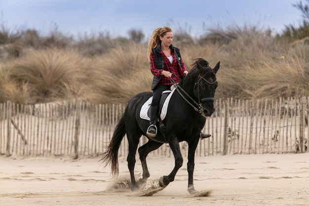 Giovane donna a cavallo sulla spiaggia