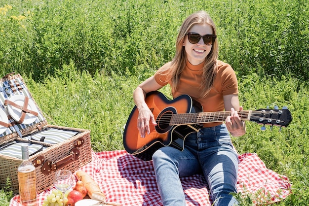 Giovane donna a suonare la chitarra su un picnic