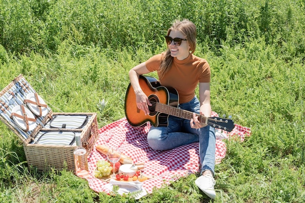 Giovane donna a suonare la chitarra su un picnic