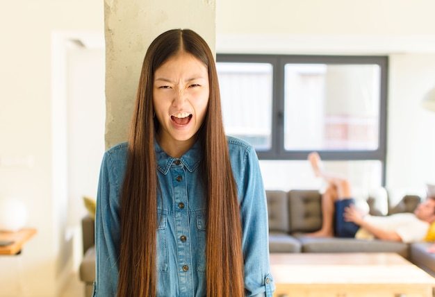 Giovane donna abbastanza asiatica che grida in modo aggressivo, sembra molto arrabbiata, frustrata, indignata o infastidita, urlando no