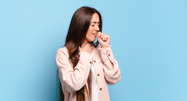 Giovane donna abbastanza casual che si sente male con mal di gola e sintomi influenzali, tosse con la bocca coperta