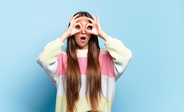 Giovane donna abbastanza casual che si sente scioccata, stupita e sorpresa, con in mano gli occhiali con uno sguardo stupito e incredulo