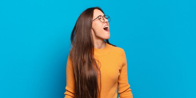 Giovane donna abbastanza casual che urla furiosamente, gridando in modo aggressivo, guardando stressata e arrabbiata