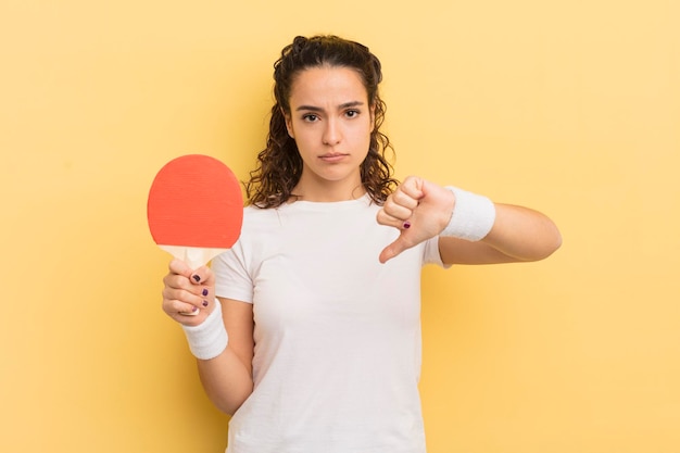 Giovane donna abbastanza ispanica che si sente crossshowing pollice verso il concetto di ping pong