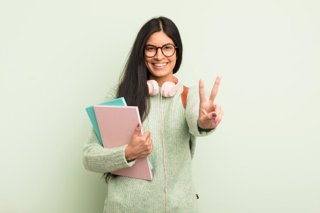 Giovane donna abbastanza ispanica che sorride e che sembra amichevole che mostra il concetto dello studente numero due