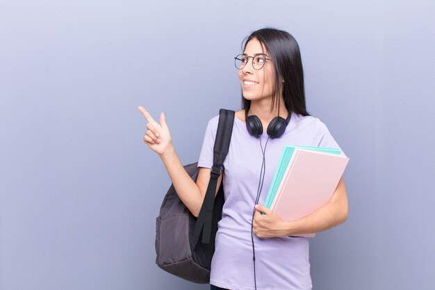 Giovane donna abbastanza latina dello studente contro la parete grigia