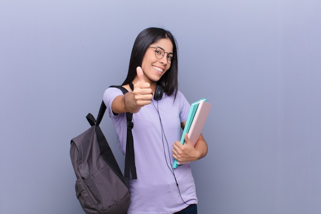 Giovane donna abbastanza latina dello studente contro la parete grigia