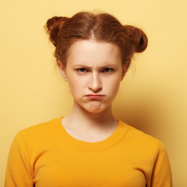 Giovane donna accigliata del redhair che pensa sul giallo