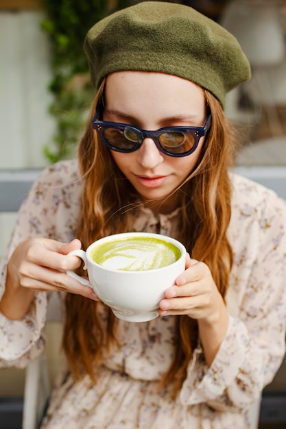 Giovane donna ad alto angolo che tiene la tazza del latte del matcha