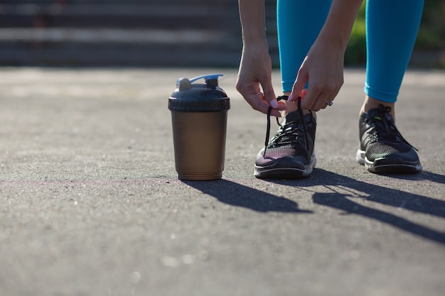 Giovane donna adatta che lega i lacci delle scarpe allo stadio durante il jogging. Spazio per il testo