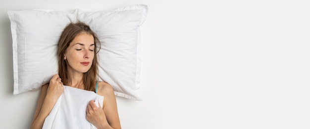 Giovane donna addormentata sdraiata su un letto bianco Banner piatto con vista dall'alto