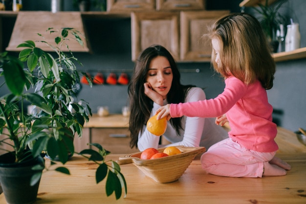 Giovane donna adorabile che gioca con la sua piccola figlia divertente in cucina.