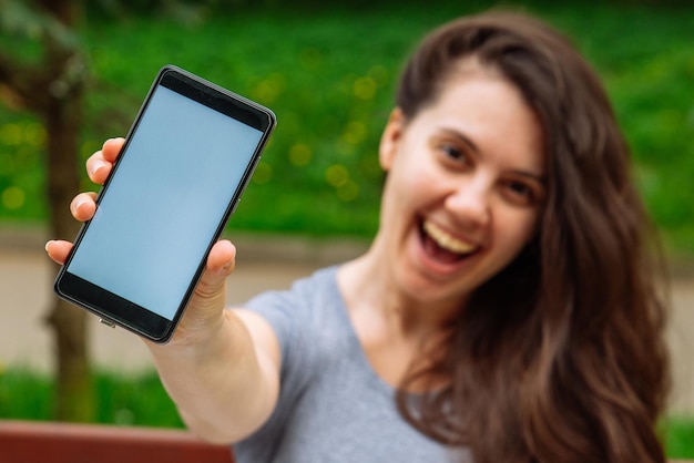 Giovane donna adulta che mostra il telefono con lo spazio bianco della copia dello schermo