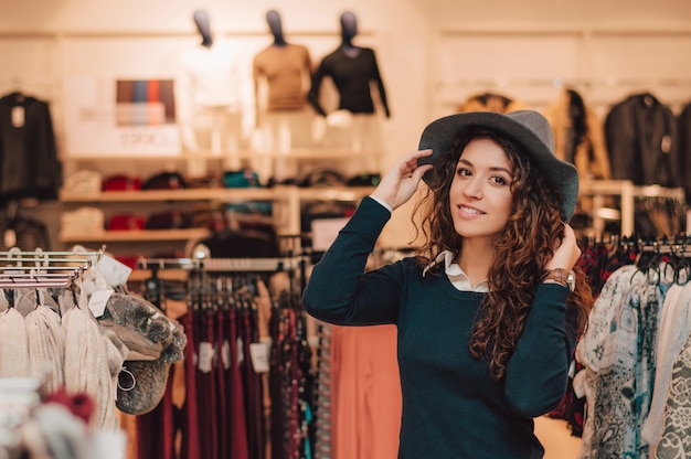 Giovane donna adulta che prova sul cappello in una vendita al dettaglio.