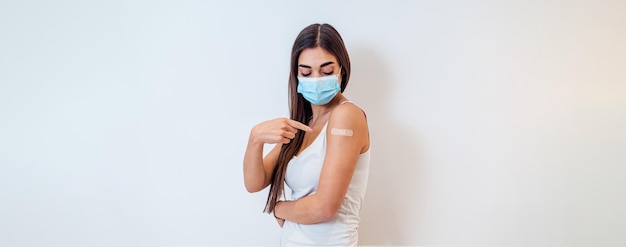 Giovane donna adulta in buona salute che indossa una maschera che punta alla benda dopo il vaccino