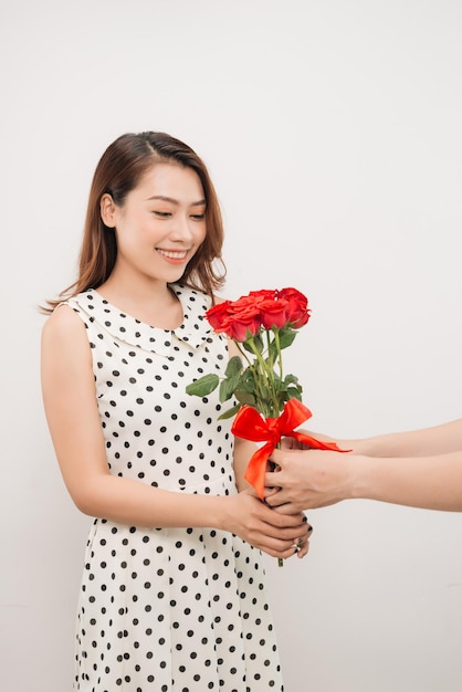 Giovane donna affascinante allegra che riceve il mazzo di fiori dal suo ragazzo sopra priorità bassa bianca